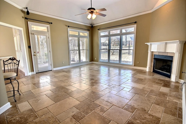 unfurnished living room with ornamental molding, a tiled fireplace, and ceiling fan