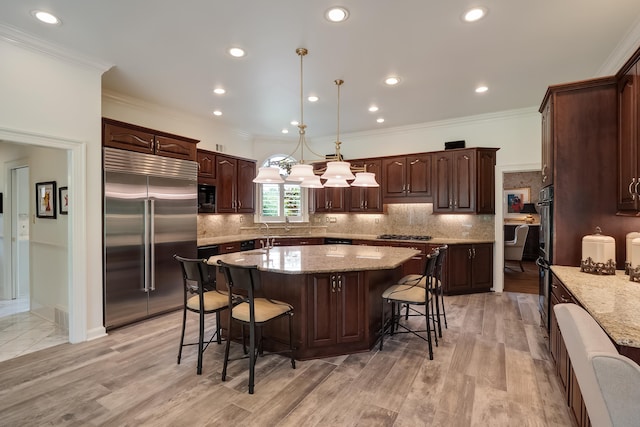 kitchen with light stone countertops, built in appliances, light hardwood / wood-style flooring, and a kitchen island