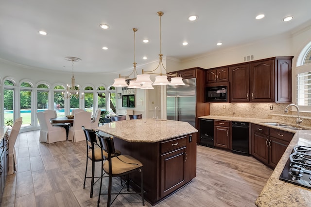 kitchen featuring tasteful backsplash, decorative light fixtures, black appliances, a kitchen island, and sink