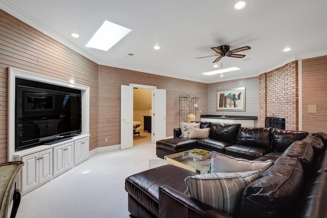 carpeted living room featuring ceiling fan, a wood stove, brick wall, ornamental molding, and a skylight