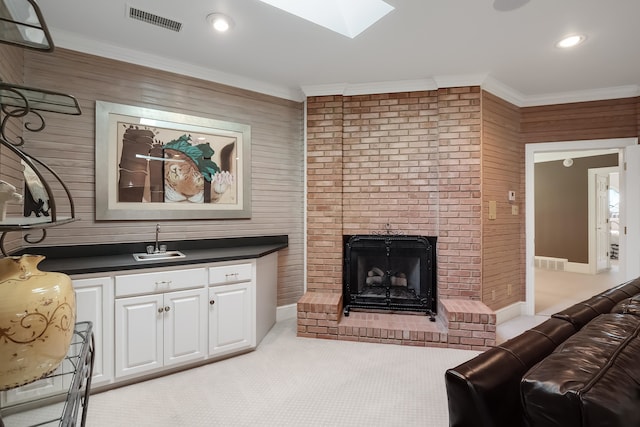 living room featuring a fireplace, wood walls, a skylight, and light colored carpet