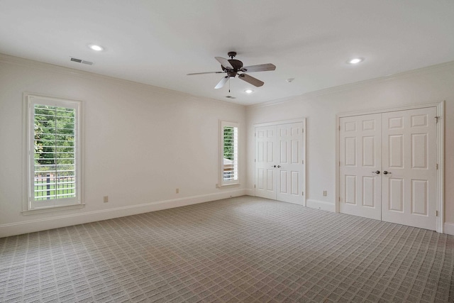 carpeted spare room with plenty of natural light, ceiling fan, and ornamental molding