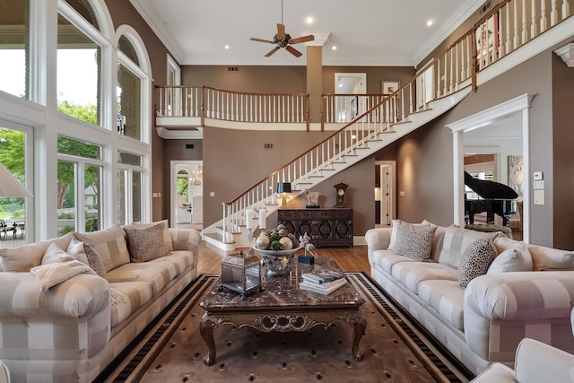 living room with a high ceiling, ceiling fan, ornamental molding, and hardwood / wood-style flooring