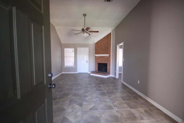 unfurnished living room with ceiling fan, a fireplace, brick wall, tile floors, and lofted ceiling