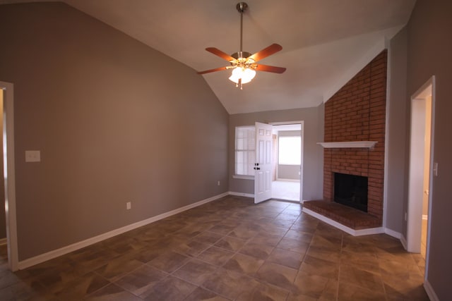 unfurnished living room featuring a fireplace, dark tile flooring, ceiling fan, and vaulted ceiling