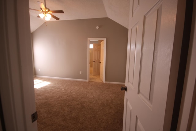 spare room featuring a textured ceiling, carpet flooring, ceiling fan, and vaulted ceiling