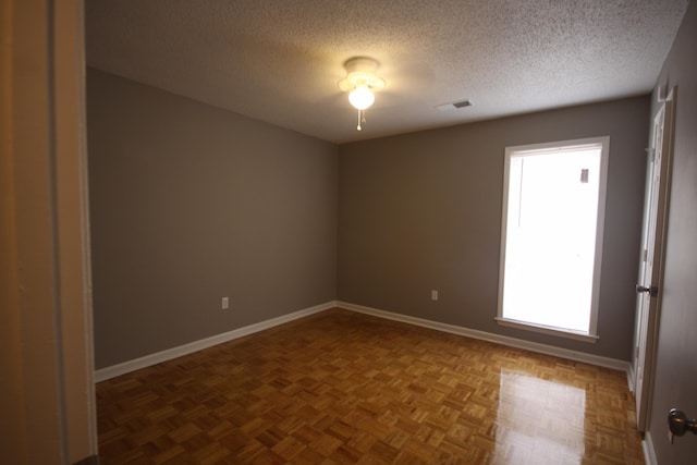 spare room with a textured ceiling and parquet floors