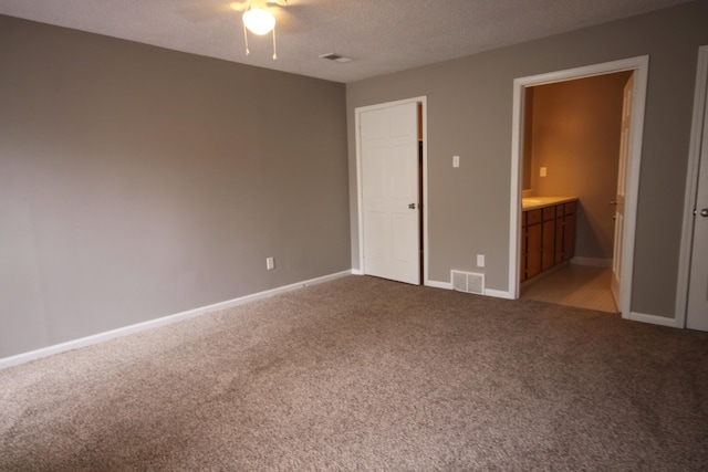 unfurnished bedroom with connected bathroom, carpet, ceiling fan, and a textured ceiling