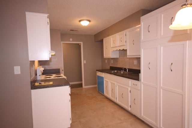 kitchen with tasteful backsplash, stove, light tile floors, sink, and white cabinetry