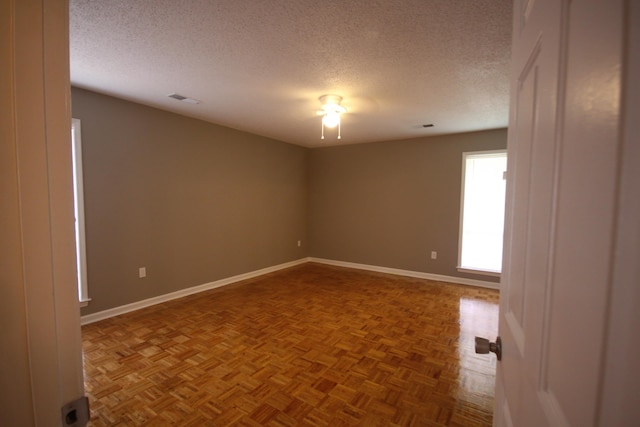 unfurnished room with parquet flooring and a textured ceiling