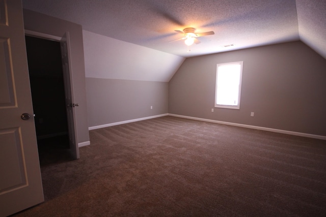 bonus room with ceiling fan, vaulted ceiling, a textured ceiling, and dark carpet