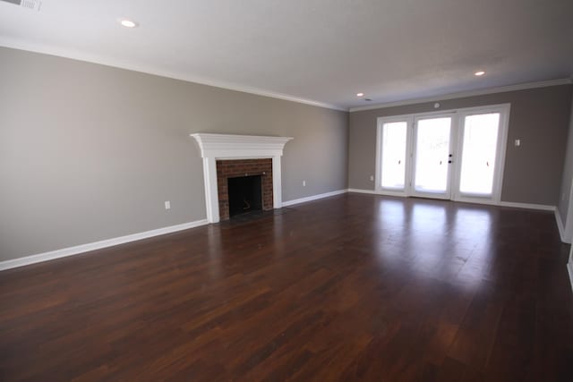 unfurnished living room with dark hardwood / wood-style floors, ornamental molding, french doors, and a fireplace