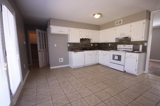 kitchen with backsplash, a wealth of natural light, white cabinets, white appliances, and light tile floors