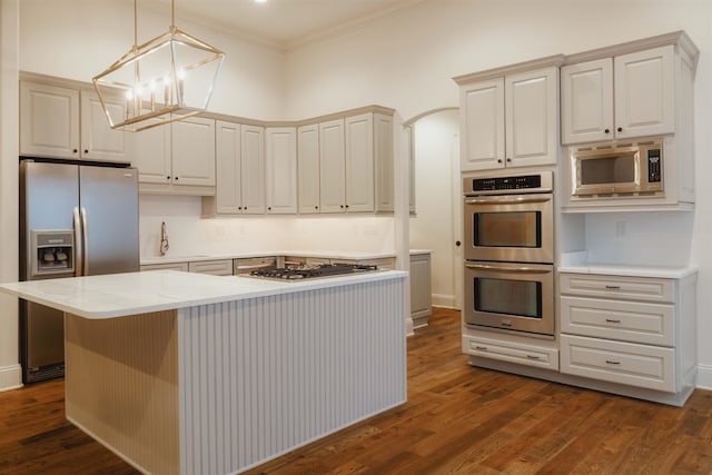 kitchen with dark hardwood / wood-style floors, crown molding, a center island, appliances with stainless steel finishes, and pendant lighting