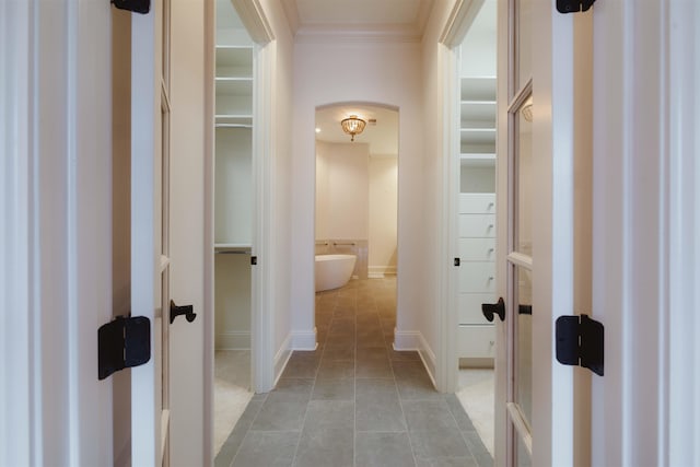 corridor with crown molding and light tile floors