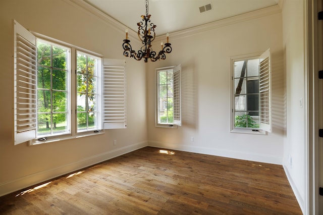 empty room featuring a healthy amount of sunlight, hardwood / wood-style floors, and an inviting chandelier