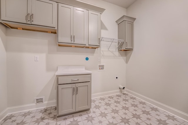 washroom featuring electric dryer hookup, cabinets, washer hookup, and light tile patterned floors