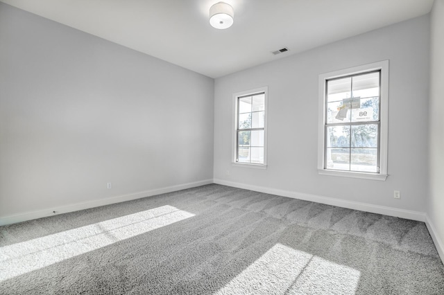 carpeted spare room featuring baseboards and visible vents