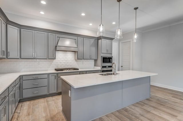 kitchen featuring light hardwood / wood-style floors, stainless steel appliances, a kitchen island with sink, and premium range hood