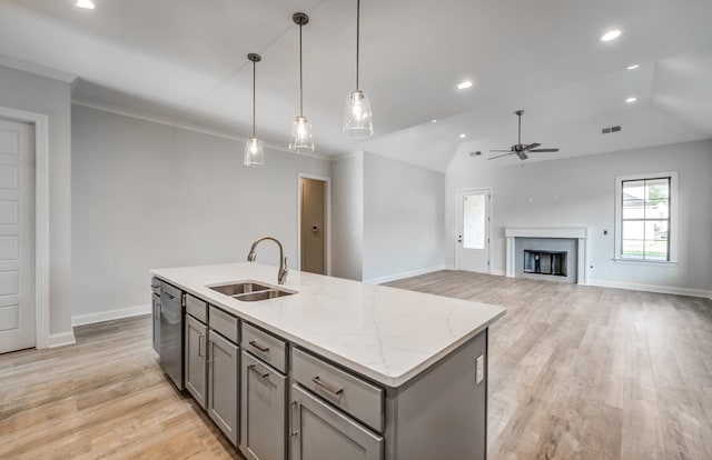 kitchen with sink, light wood-type flooring, a kitchen island with sink, ceiling fan, and a high end fireplace