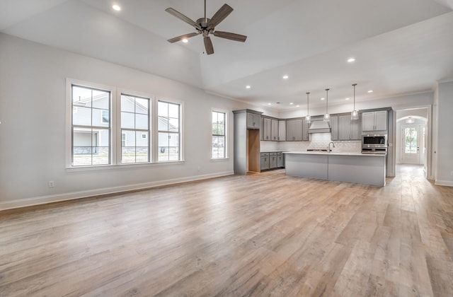 kitchen featuring custom range hood, light wood-type flooring, tasteful backsplash, ceiling fan, and gray cabinets