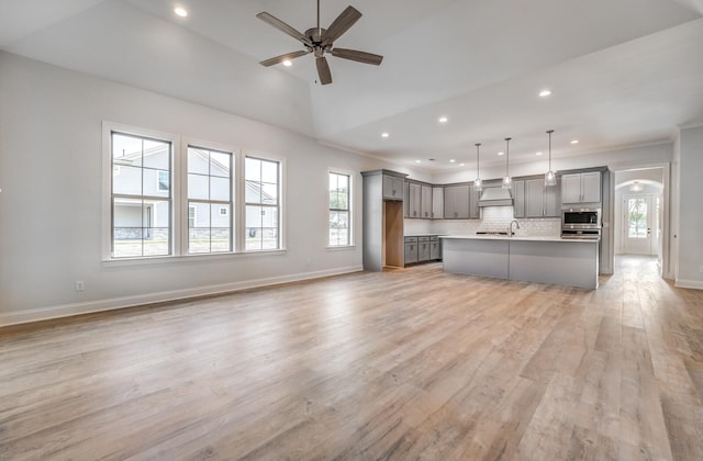 kitchen featuring open floor plan, premium range hood, stainless steel microwave, and gray cabinets