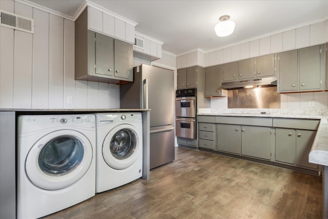 clothes washing area with washer and dryer and hardwood / wood-style floors