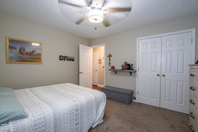 carpeted bedroom with ceiling fan, a closet, and a textured ceiling