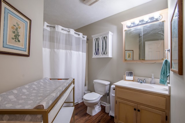 bathroom with wood-type flooring, vanity, toilet, and a textured ceiling