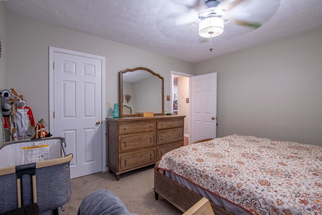 carpeted bedroom featuring ceiling fan and a textured ceiling