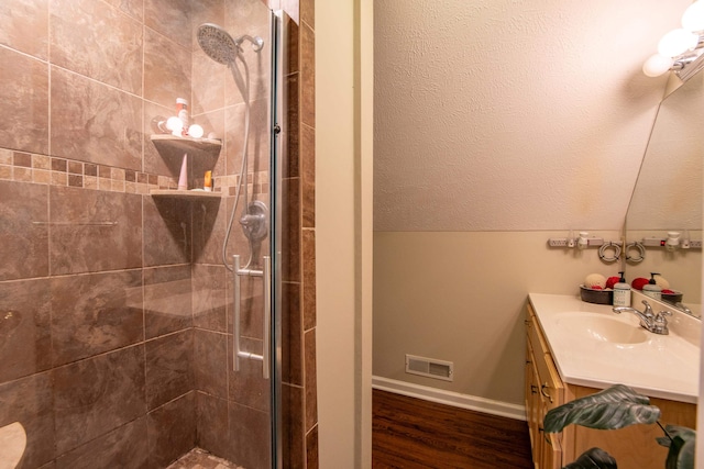 bathroom with a shower with door, vanity with extensive cabinet space, lofted ceiling, and wood-type flooring