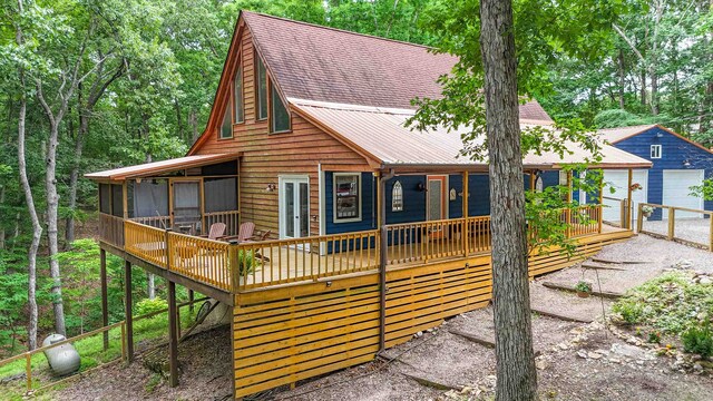 log-style house with an outdoor structure, a garage, and a wooden deck