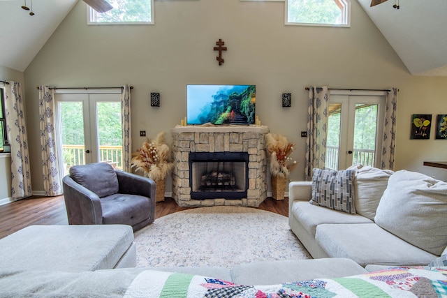 living room featuring high vaulted ceiling, hardwood / wood-style flooring, a fireplace, and french doors