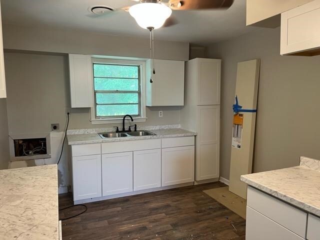 kitchen featuring a fireplace, white cabinets, dark hardwood / wood-style floors, sink, and ceiling fan