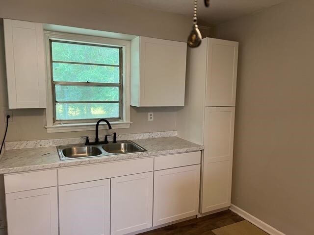 kitchen featuring decorative light fixtures, sink, white cabinets, and a healthy amount of sunlight