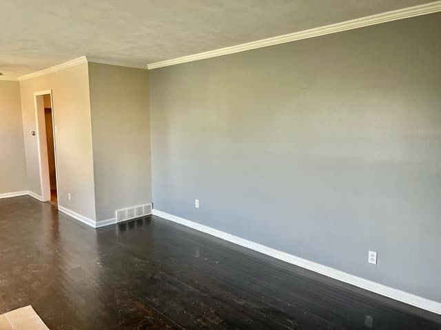 spare room with dark wood-type flooring and crown molding