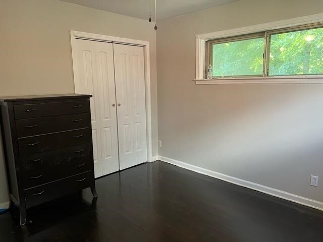 unfurnished bedroom featuring a closet and dark hardwood / wood-style flooring