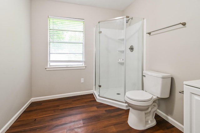 bathroom with hardwood / wood-style flooring, vanity, toilet, and a shower with shower door