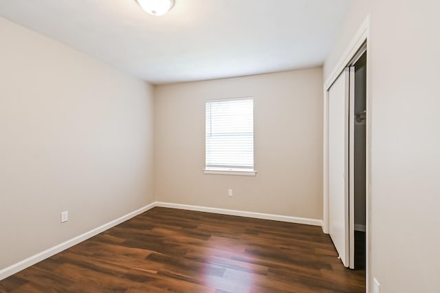 unfurnished bedroom with dark hardwood / wood-style flooring and a closet