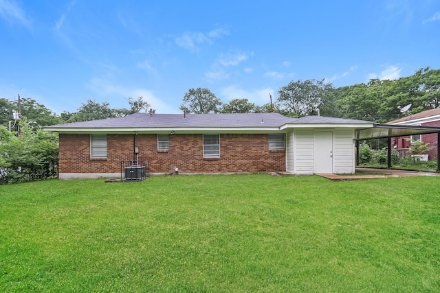 rear view of property with a carport, a yard, and central air condition unit