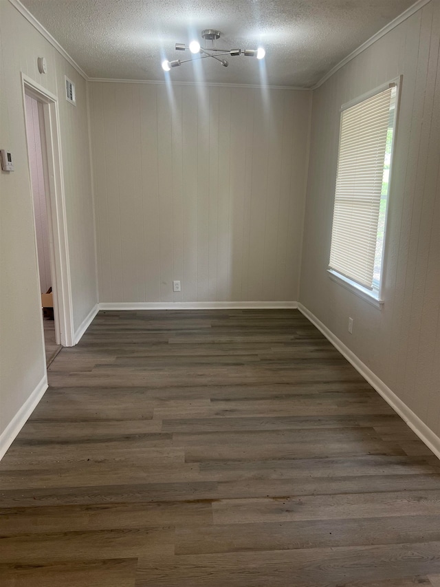 unfurnished room with a textured ceiling, crown molding, and dark wood-type flooring