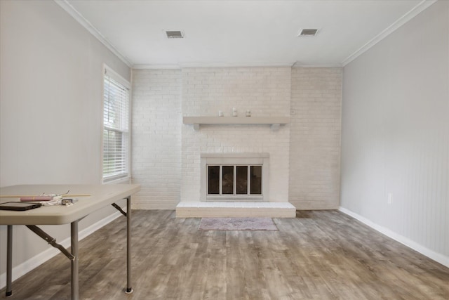 unfurnished living room featuring hardwood / wood-style flooring, crown molding, brick wall, and a brick fireplace