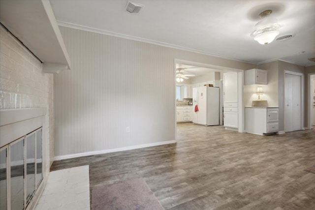 unfurnished living room featuring light hardwood / wood-style floors, a brick fireplace, ceiling fan, and ornamental molding