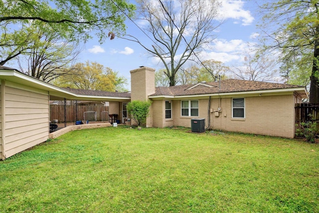 rear view of house featuring central air condition unit and a yard