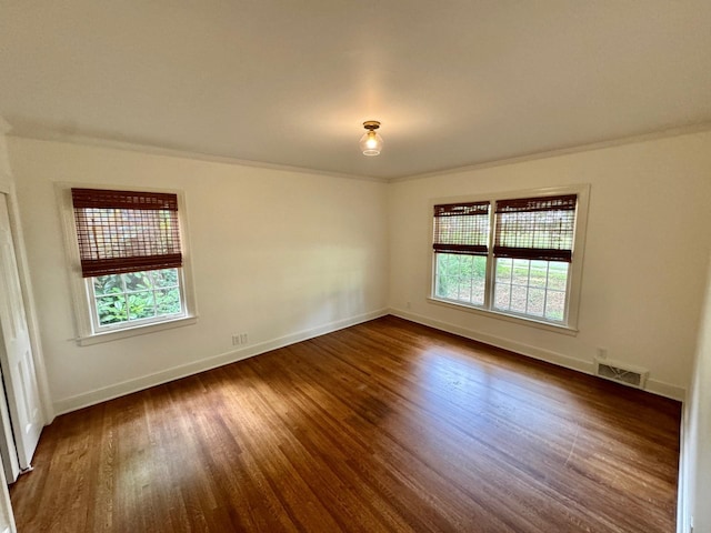 spare room featuring dark wood-type flooring and ornamental molding