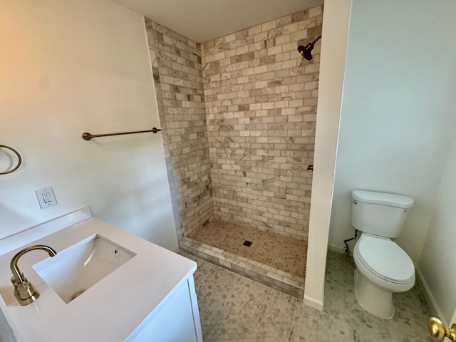 bathroom featuring tile patterned flooring, vanity, toilet, and a tile shower