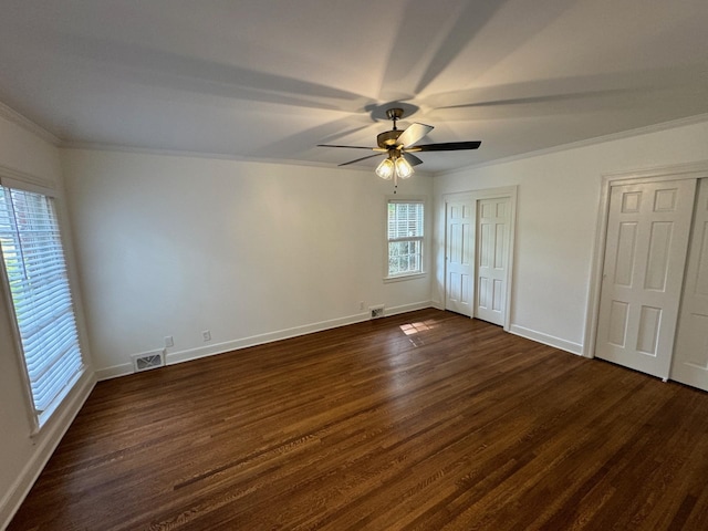 unfurnished bedroom featuring ceiling fan, dark hardwood / wood-style flooring, ornamental molding, and two closets