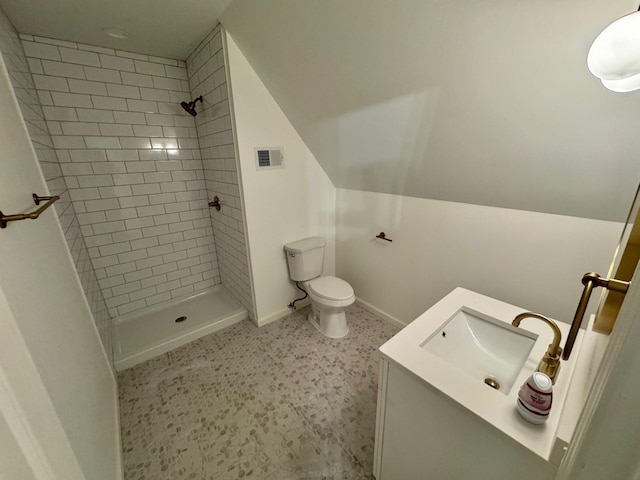 bathroom featuring a tile shower, vanity, and toilet