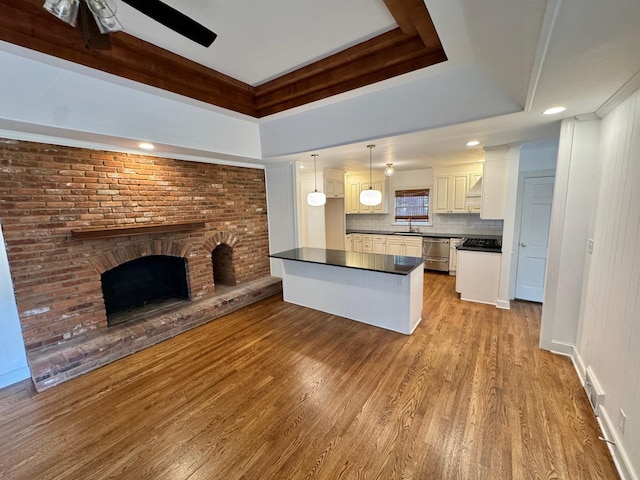 kitchen featuring pendant lighting, stainless steel dishwasher, white cabinetry, and light hardwood / wood-style flooring