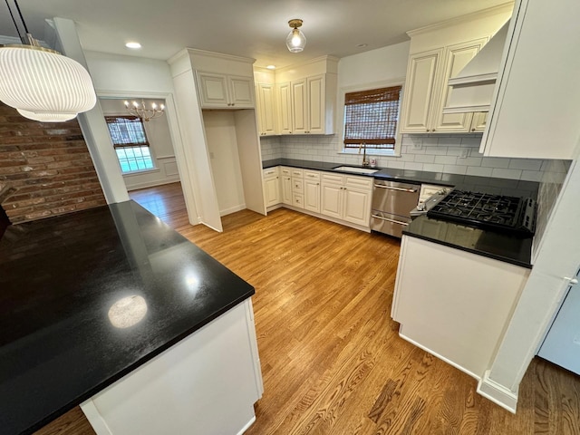 kitchen featuring pendant lighting, sink, light hardwood / wood-style flooring, tasteful backsplash, and white cabinetry